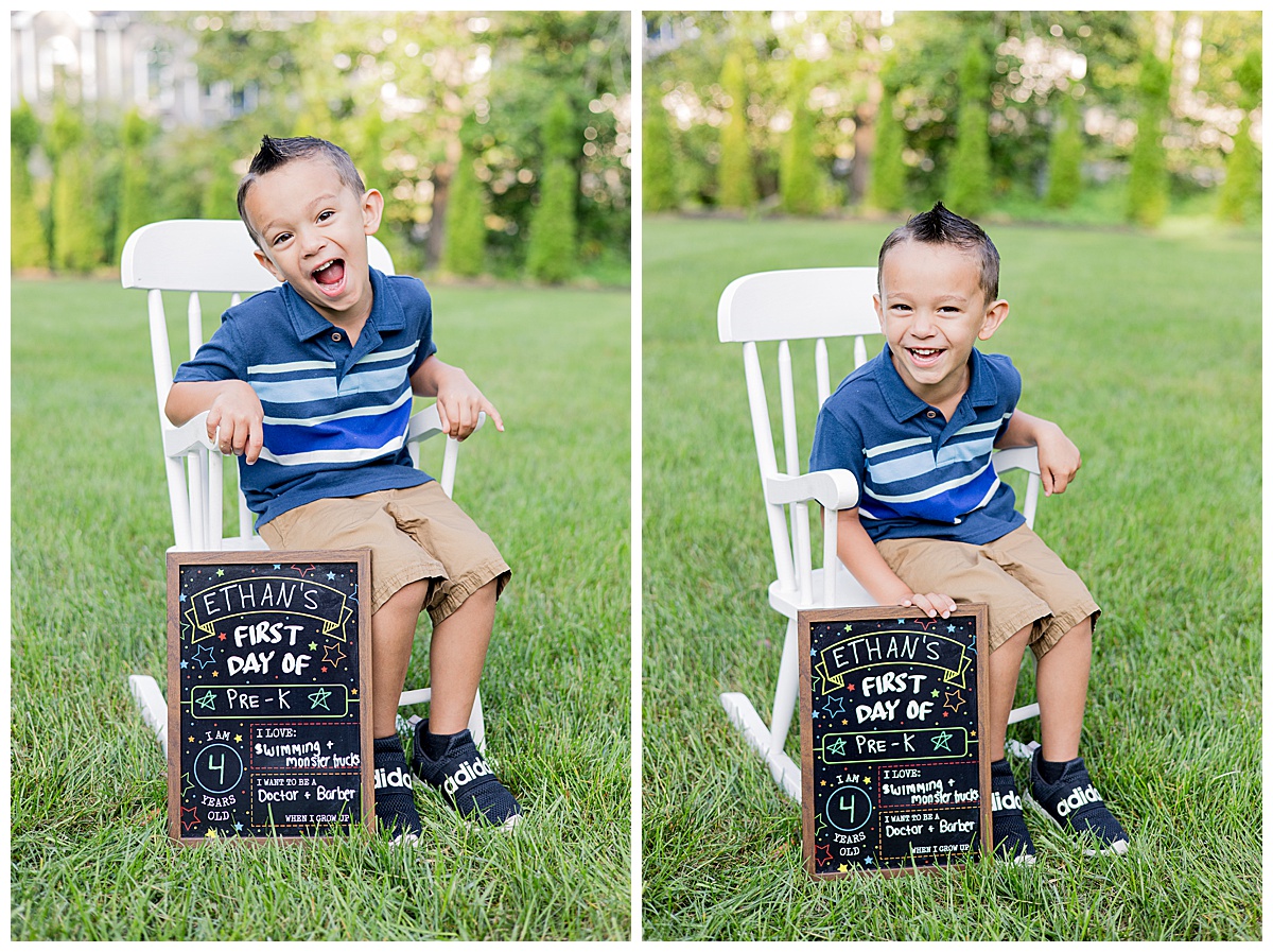 Ethan sitting on a white chair outdoors, with a green garden in the background. He's holding the same chalkboard sign from earlier. Photo taken in Westport, MA by family photographer Lorie-Lyn Photography